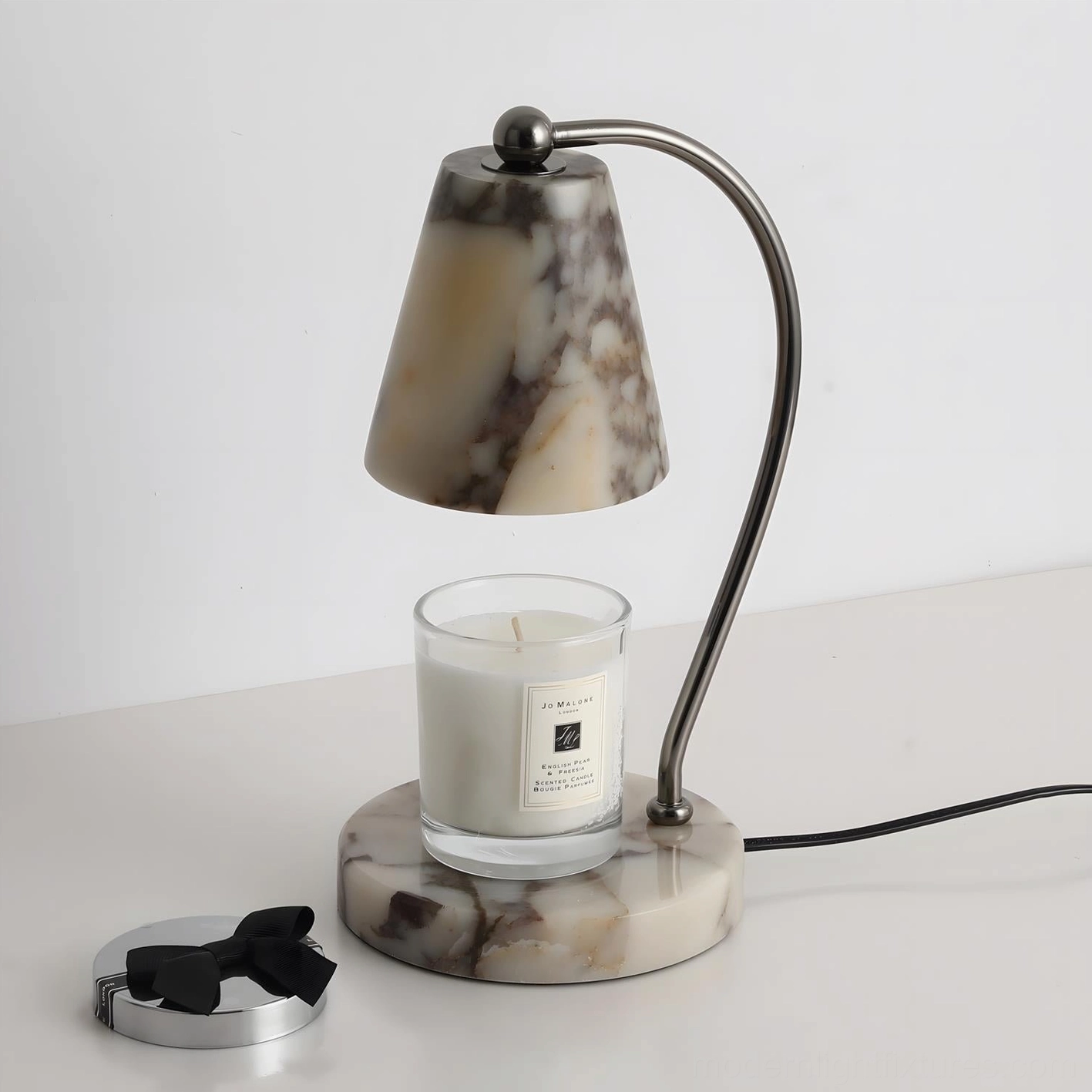 Contemporary table candle warmer lamp with marble shade and base, three-quarter perspective with lit scented candle