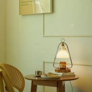 Contemporary candle warmer lamp displayed on wooden side table in warm home interior setting with books