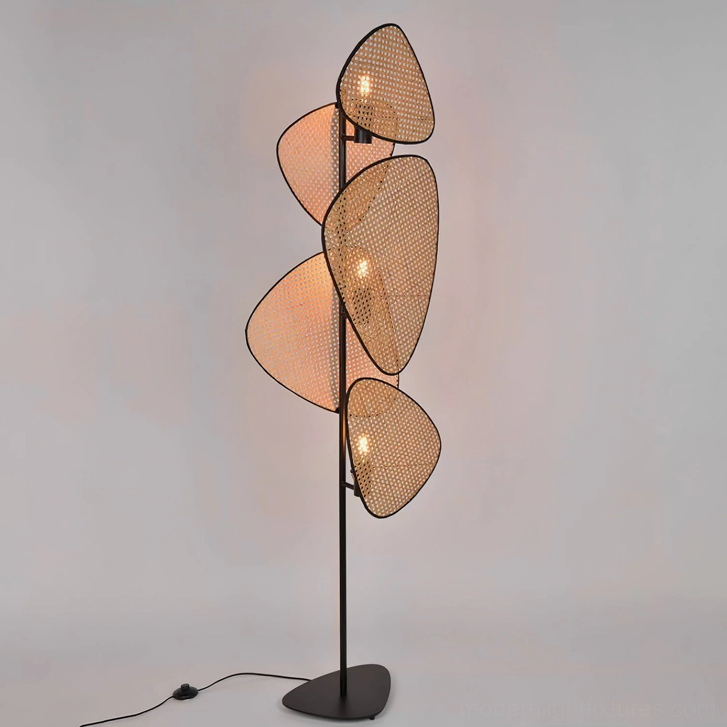 Cannage rattan floor lamp illuminated front straight view with perforated panels creating light diffusion
