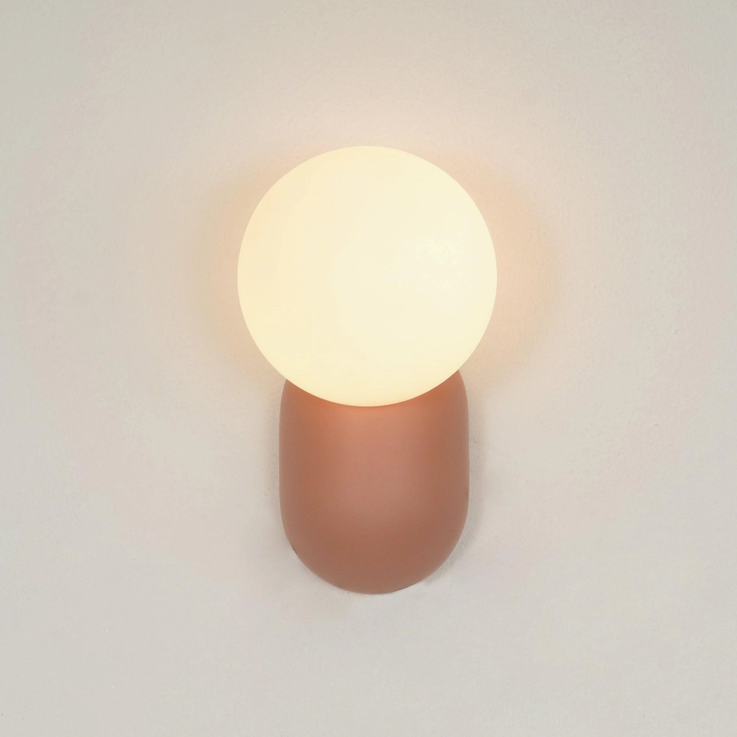 Modern cantilever wall sconce with soft light projection creating intimate bedside reading environment