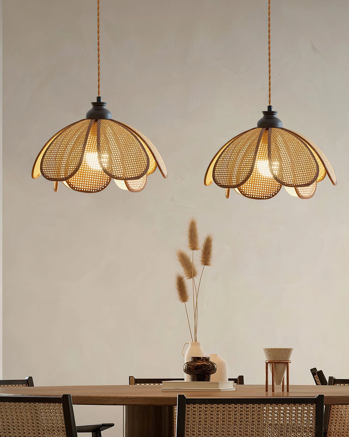 Twin Capelina rattan petal pendant lights hung over long wooden dining table in bohemian interior
