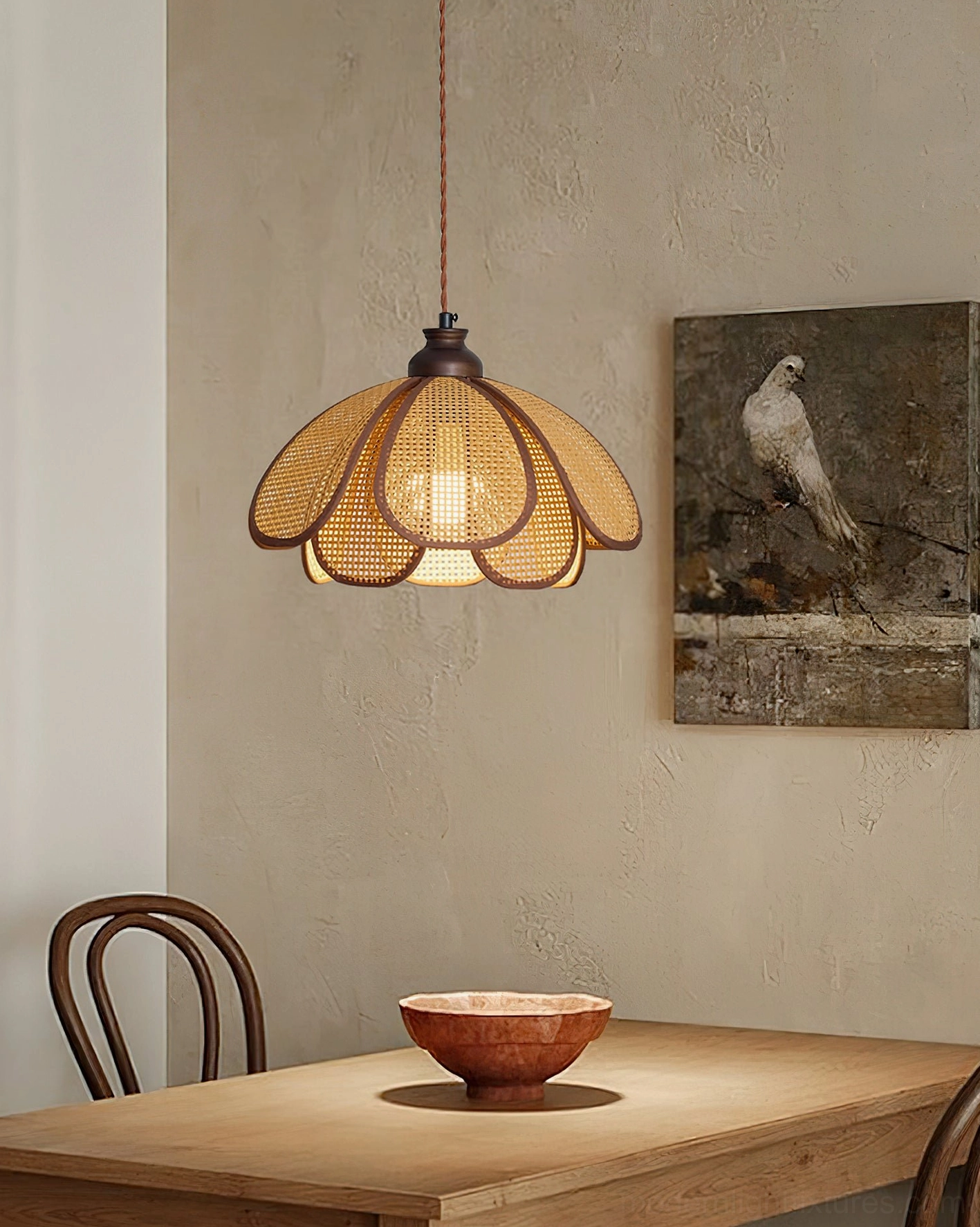 Capelina woven rattan pendant light suspended over wooden dining table with warm wabi-sabi ambiance