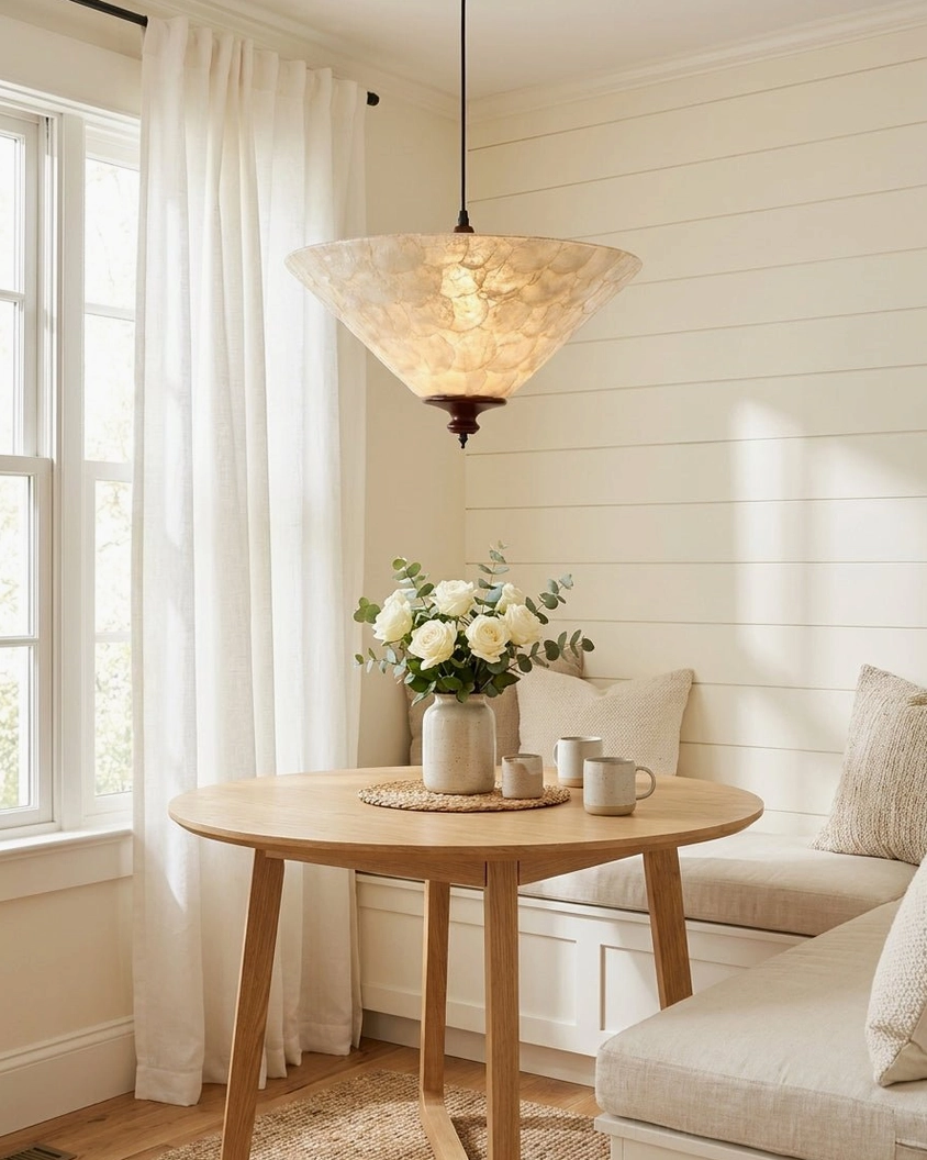 Capelle capiz shell pendant light hanging in cozy transitional dining room above round wooden table with warm ambient glow