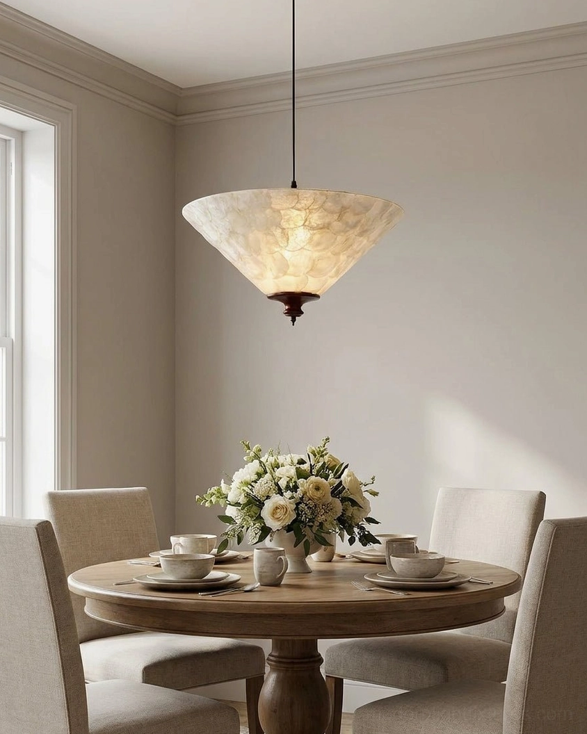 Capelle capiz shell pendant light illuminated above formal dining room table with floral centerpiece and warm dinner lighting