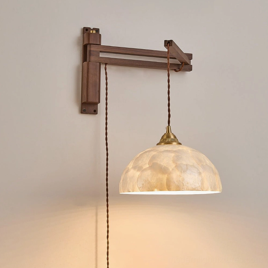 Swing-arm wall sconce detail shot showing hand-laid natural Capiz shell tiles, walnut wood arm and brass hardware