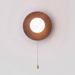 Cara wood wall sconce with warm LED light glowing through frosted glass, yellow pull chain pendant