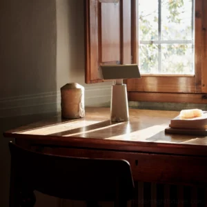White gray Caret table lamp on wooden side table with warm ambient lighting and vintage décor