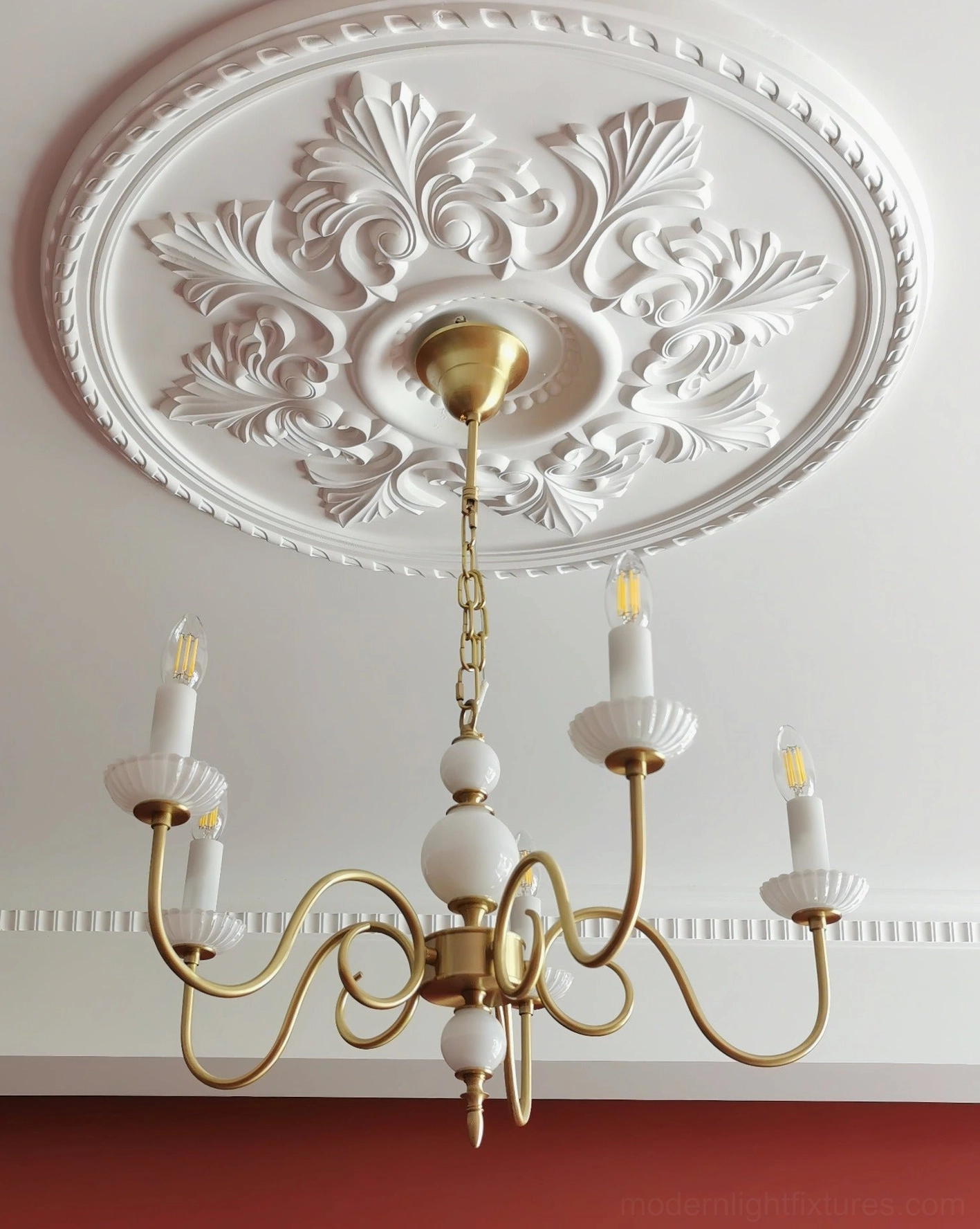 Carlita chandelier installed on decorative ceiling medallion in residential interior with red accent wall