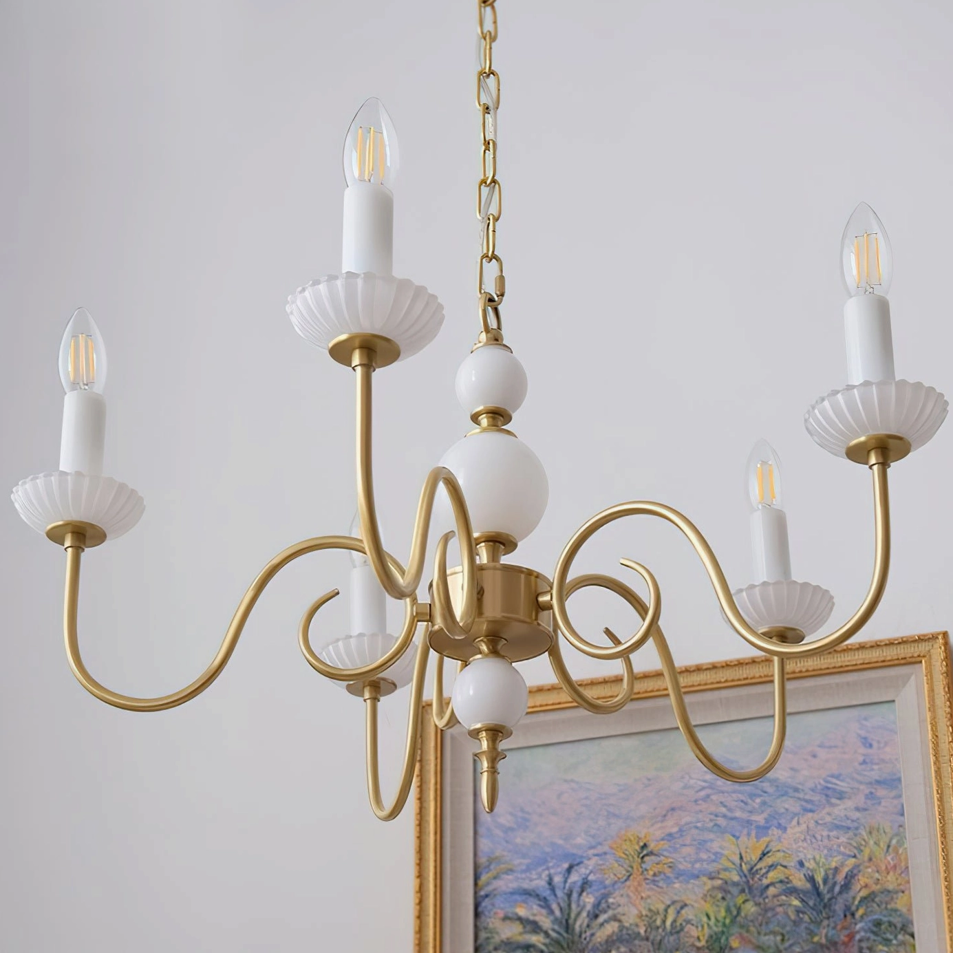 Gold curved arm chandelier with fluted white candle trays in elegant dining room setting
