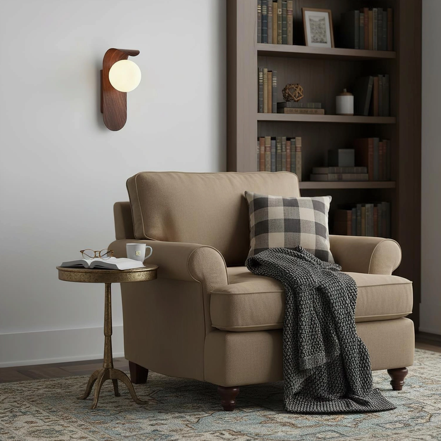 Single Carlyle wooden wall sconce beside upholstered armchair in cozy reading lounge with bookshelf backdrop