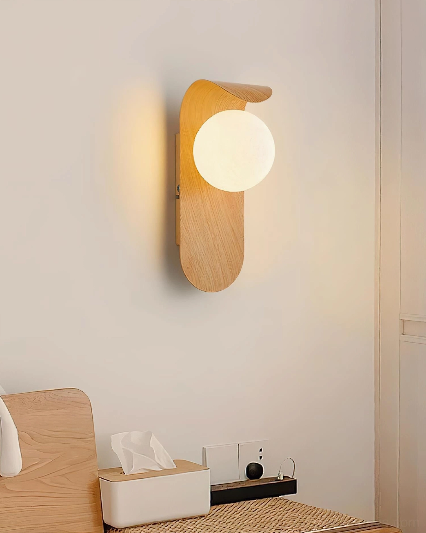 Carlyle wall sconce with frosted glass globe casting soft warm light on textured wall surface
