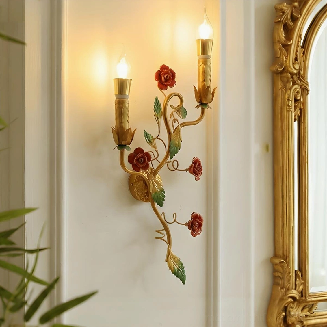 Red rose Carmelia wall sconce mounted close to ornate gold mirror frame in intimate bedroom ambiance