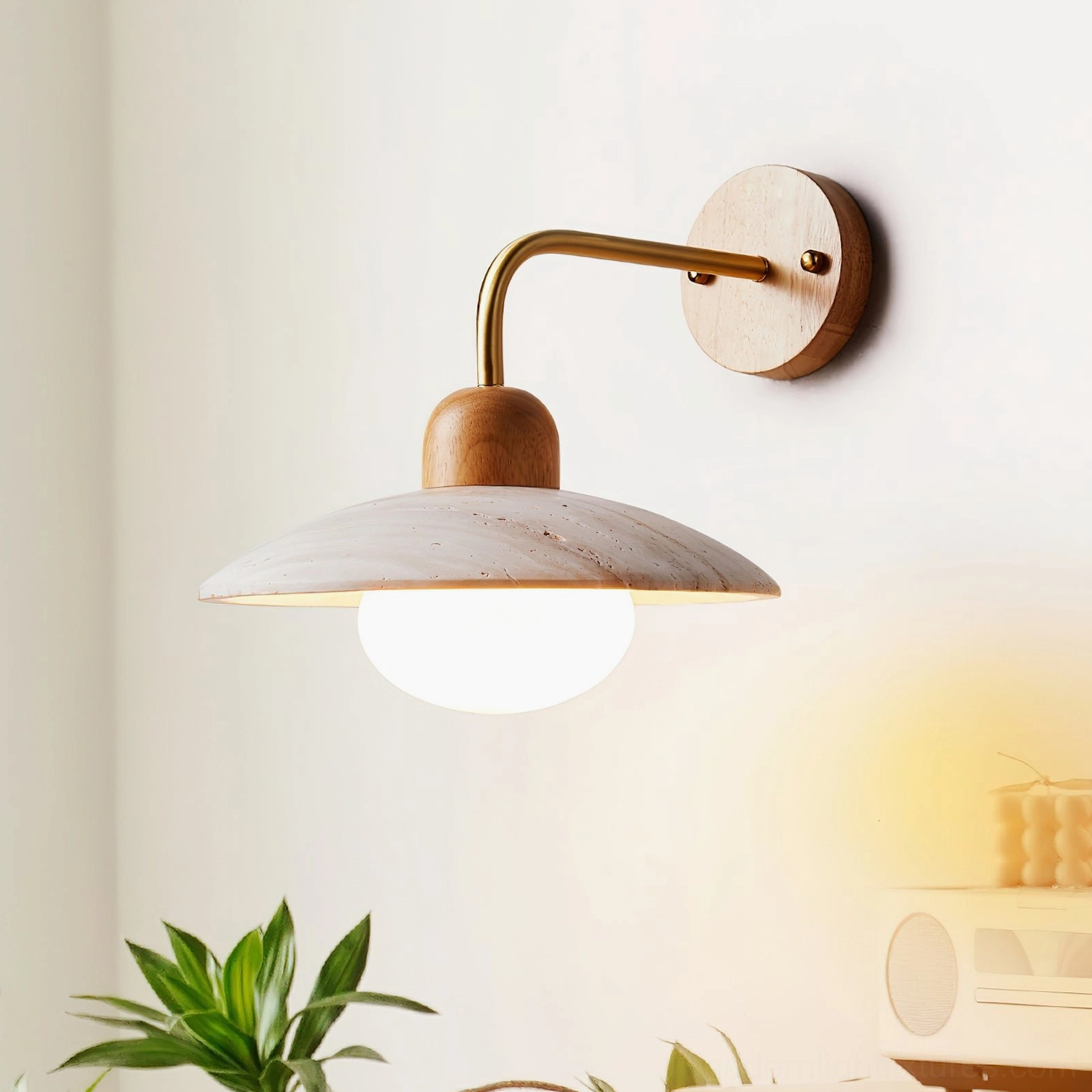 Brass and wood travertine wall lamp sconce positioned in home interior corner with green plant decor