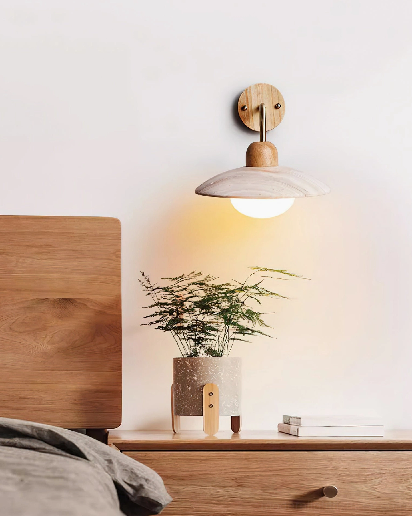Carolia wall sconce with gold brass finish showing warm metallic tone against travertine stone shade