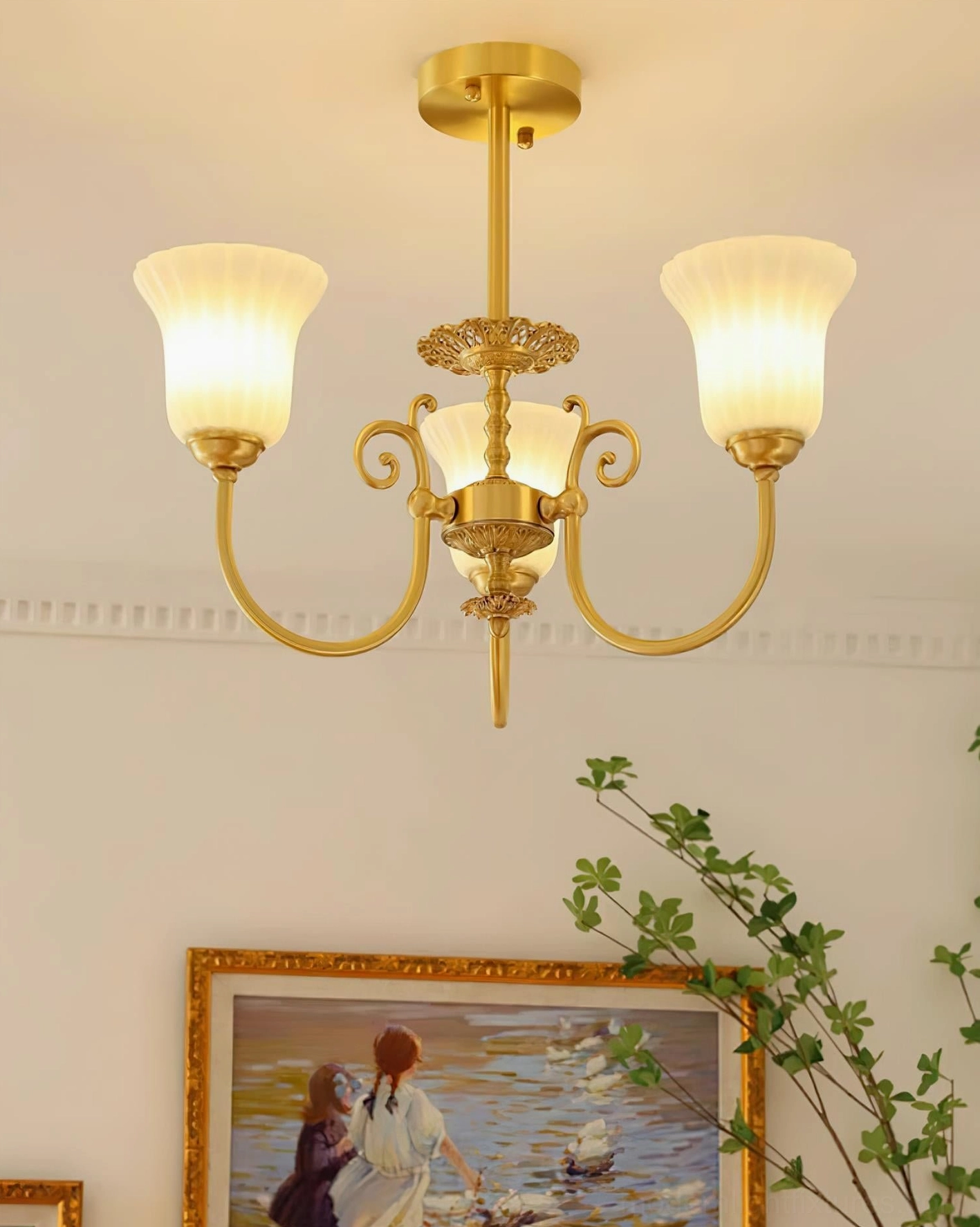 Overhead front view of 3-head brass chandelier in bright living room with wall art