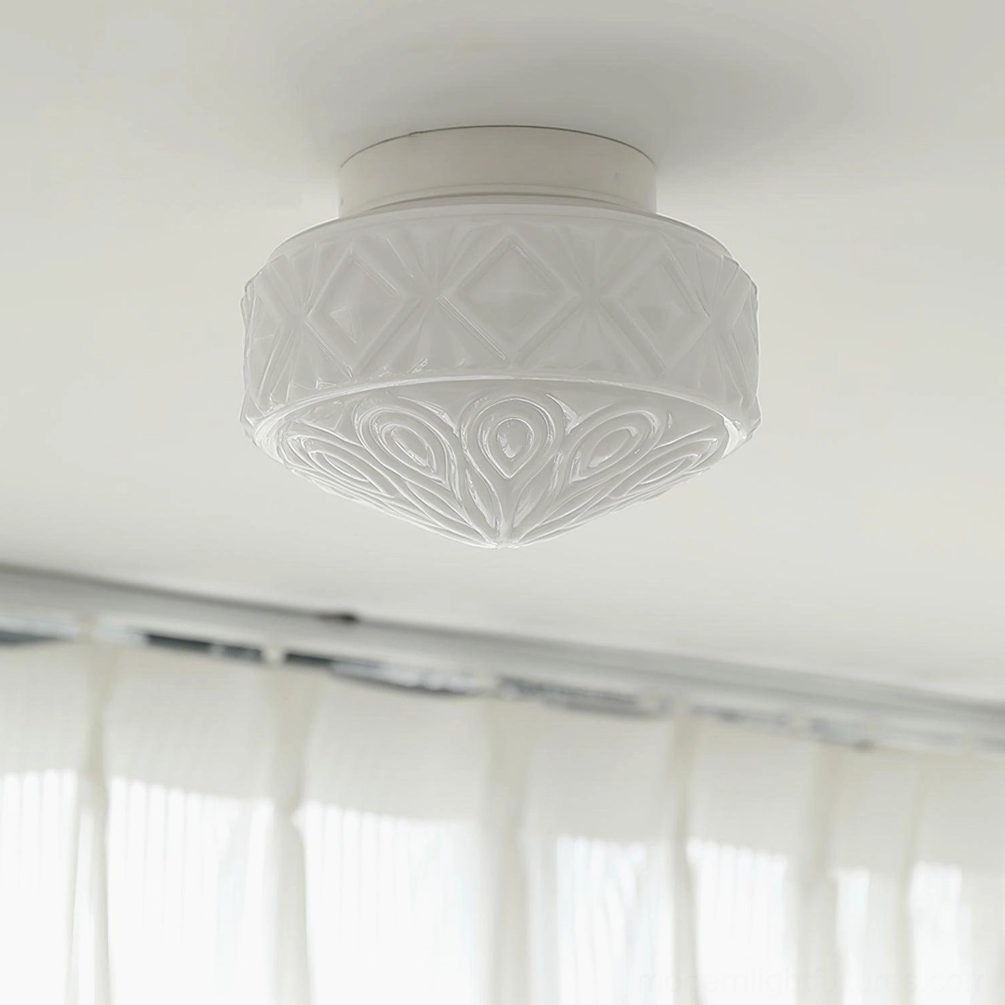 Vintage glass flush mount ceiling light installed on home ceiling, low-angle view showing carved texture and warm illumination