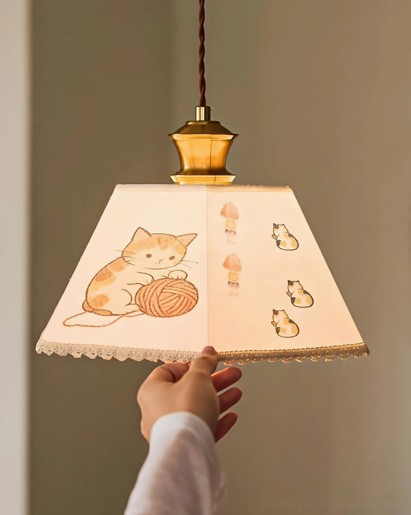 Hand-held close-up of fabric pendant light showing full shade decoration with cat motifs and details