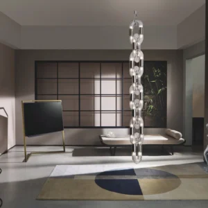 Modern acrylic ring pendant lamp installed in luxury showroom with clear stacked rings and metal hardware
