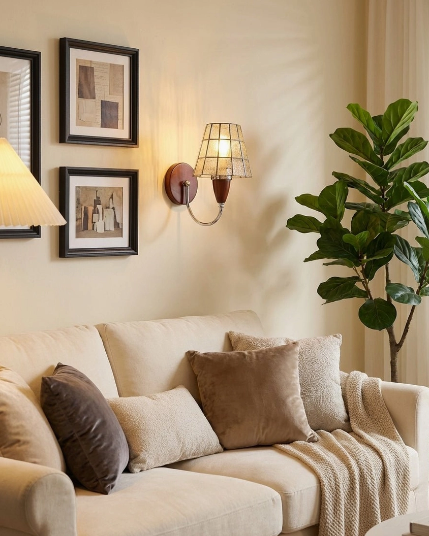 Cavero wall sconce in living room gallery wall with framed art and green potted plant creating layered lighting