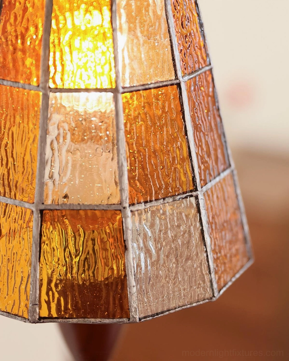 Close-up macro detail of Cavero textured stained glass panels with amber color palette and metal grid framing