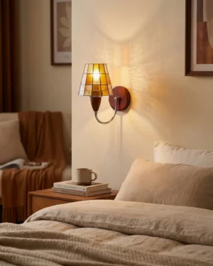 Cavero wall sconce in bedroom bedside setting with warm amber glass diffusing soft ambient light above nightstand