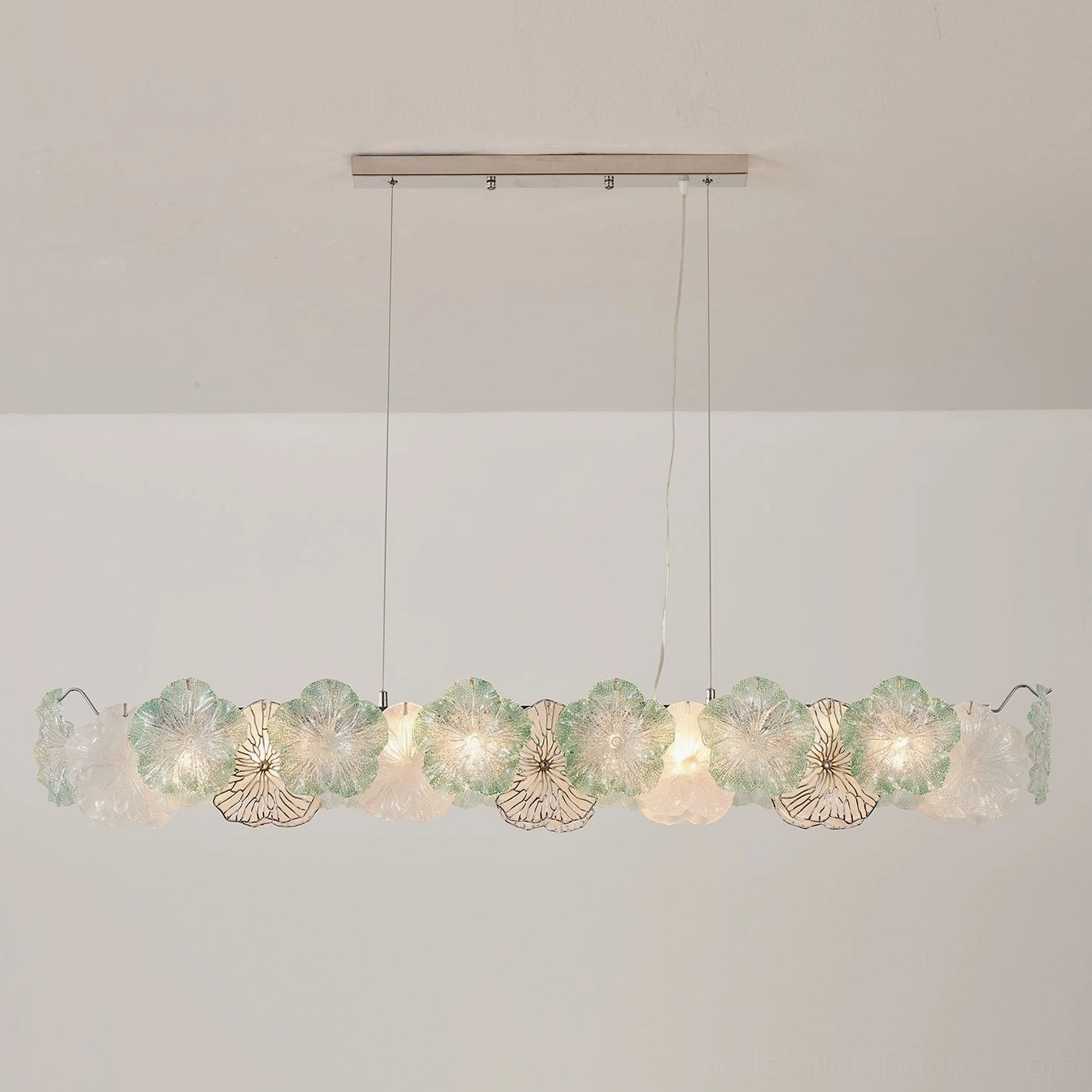 Celadine chandelier lit from below showing warm glow through hand-formed glass petals, interior ambiance design
