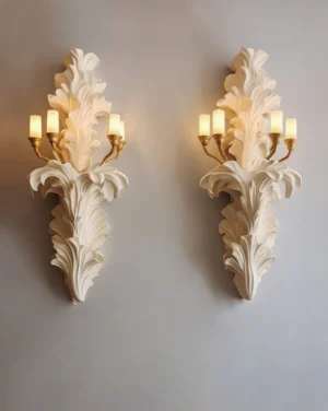 Pair of matching Celandra botanical wall sconces with acanthus leaves, brass lamp holders, and candle-style bulbs, displayed side-by-side on gray wall