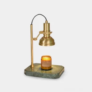 Celeste brass and marble candle warmer lamp front view on minimalist white tabletop showing brass body and dark green marble base