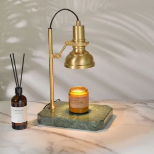 Celeste candle warmer lamp three-quarter view with reed diffuser bottle on marble table with palm leaf decor accent