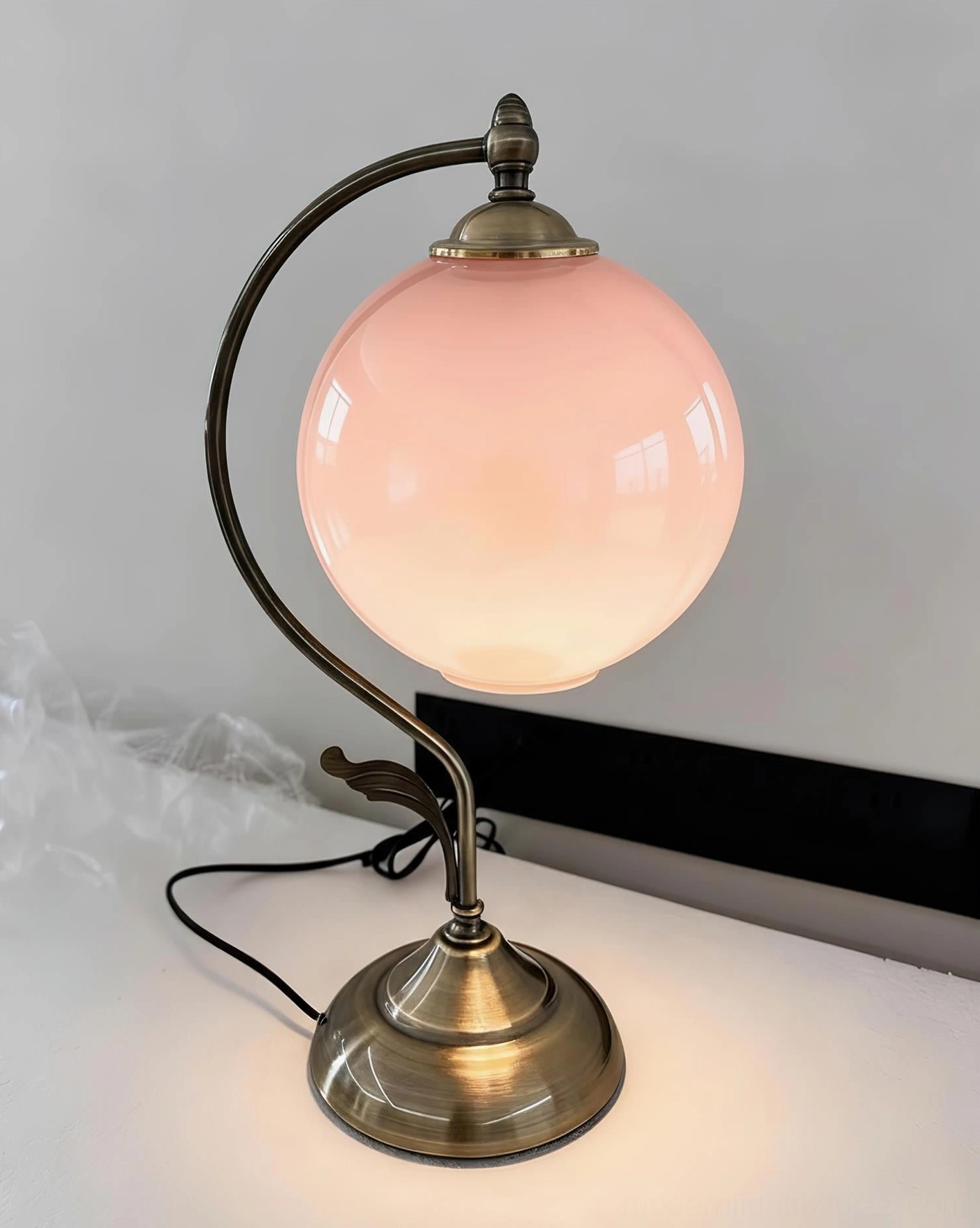 Celestial globe table lamp detail view emphasizing brass craftsmanship, glass sphere diffuser, and sculptural arm design elements