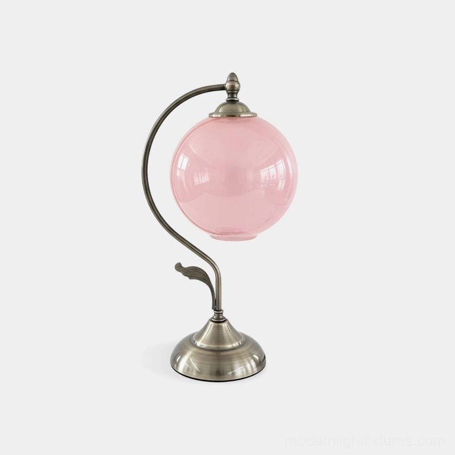 Celestial globe table lamp with curved brass arm and pink frosted glass sphere, front studio view highlighting vintage retro design