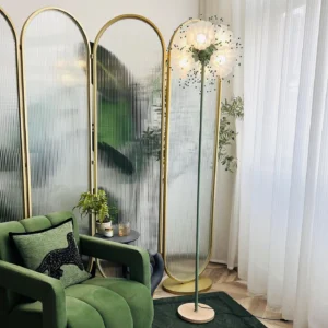 Illuminated Celonia floor lamp in luxury living room setting with green velvet sofa and gold arched screen