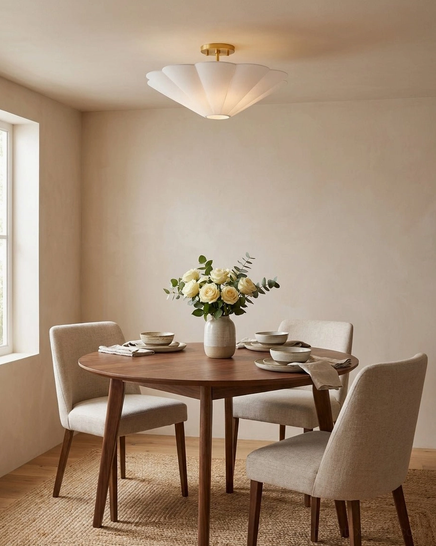 Celora semi-flush ceiling light with gold canopy illuminating dining room table with round wooden top and upholstered dining chairs