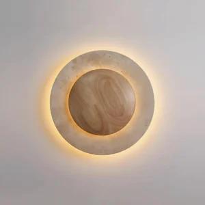 Celora wall lamp backlit circular design showing warm ambient light on textured travertine surface