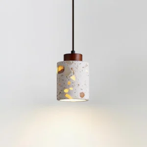 Illuminated cemento pendant lamp emitting warm ambient light through textured terrazzo material