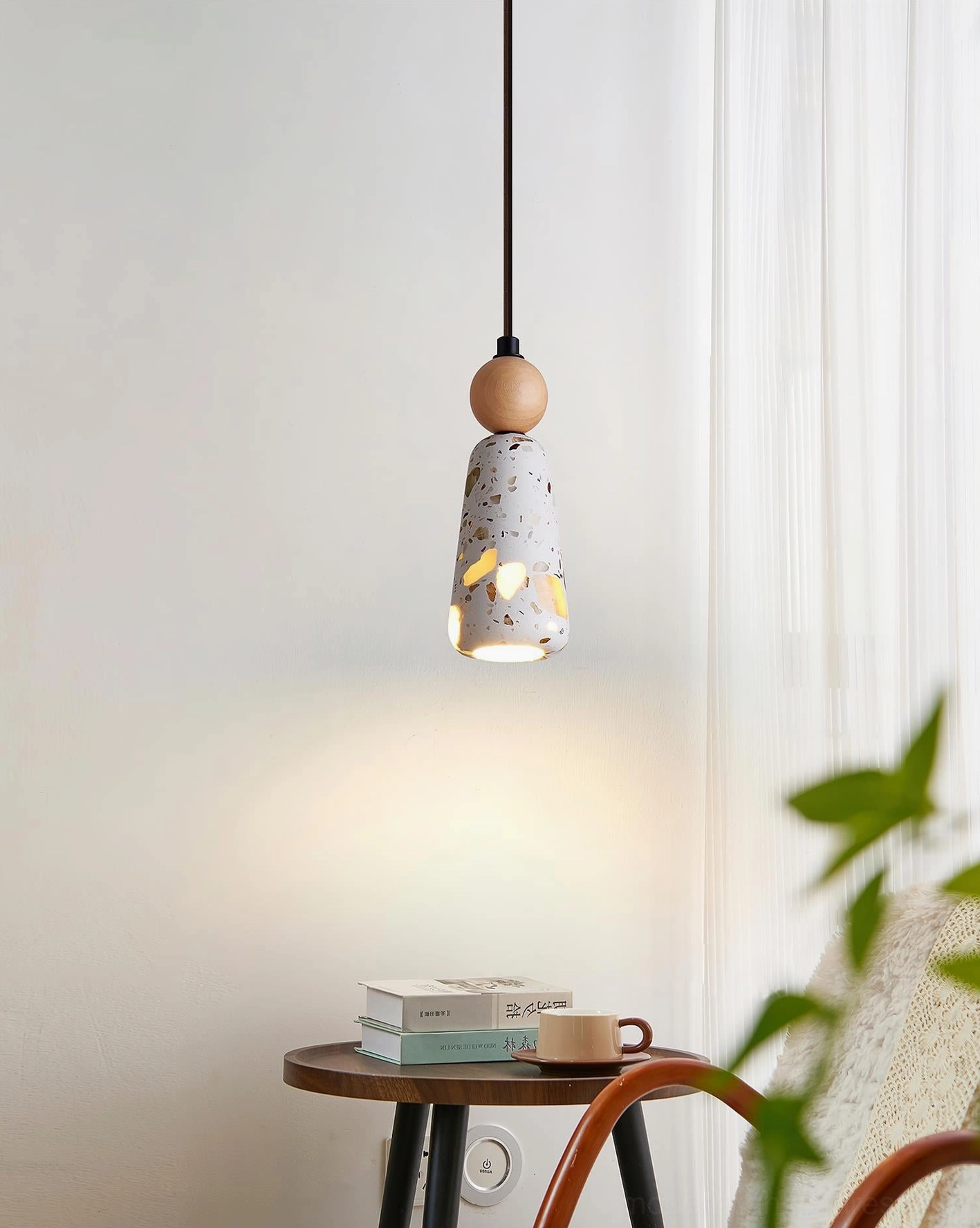Tapered terrazzo pendant lamp illuminated in living room beside wooden accent table