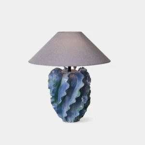 Organic ceramic blue table lamp with ruffled leaf base and grey fabric shade, front view on white background