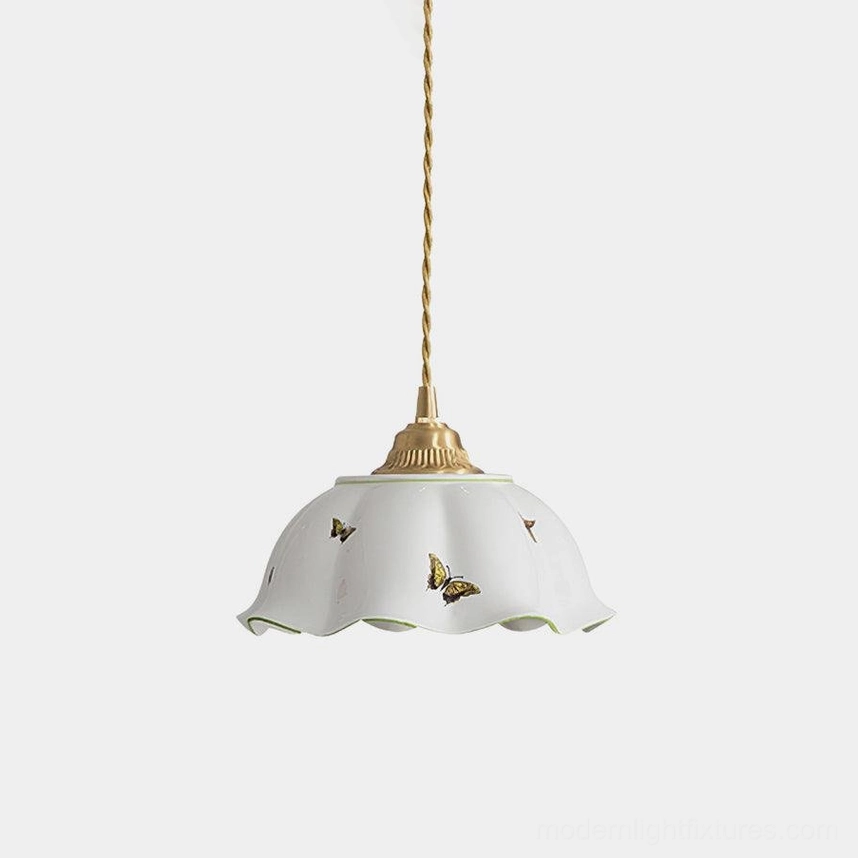 White ceramic pendant light with butterfly prints and brass hardware, front low-angle studio view