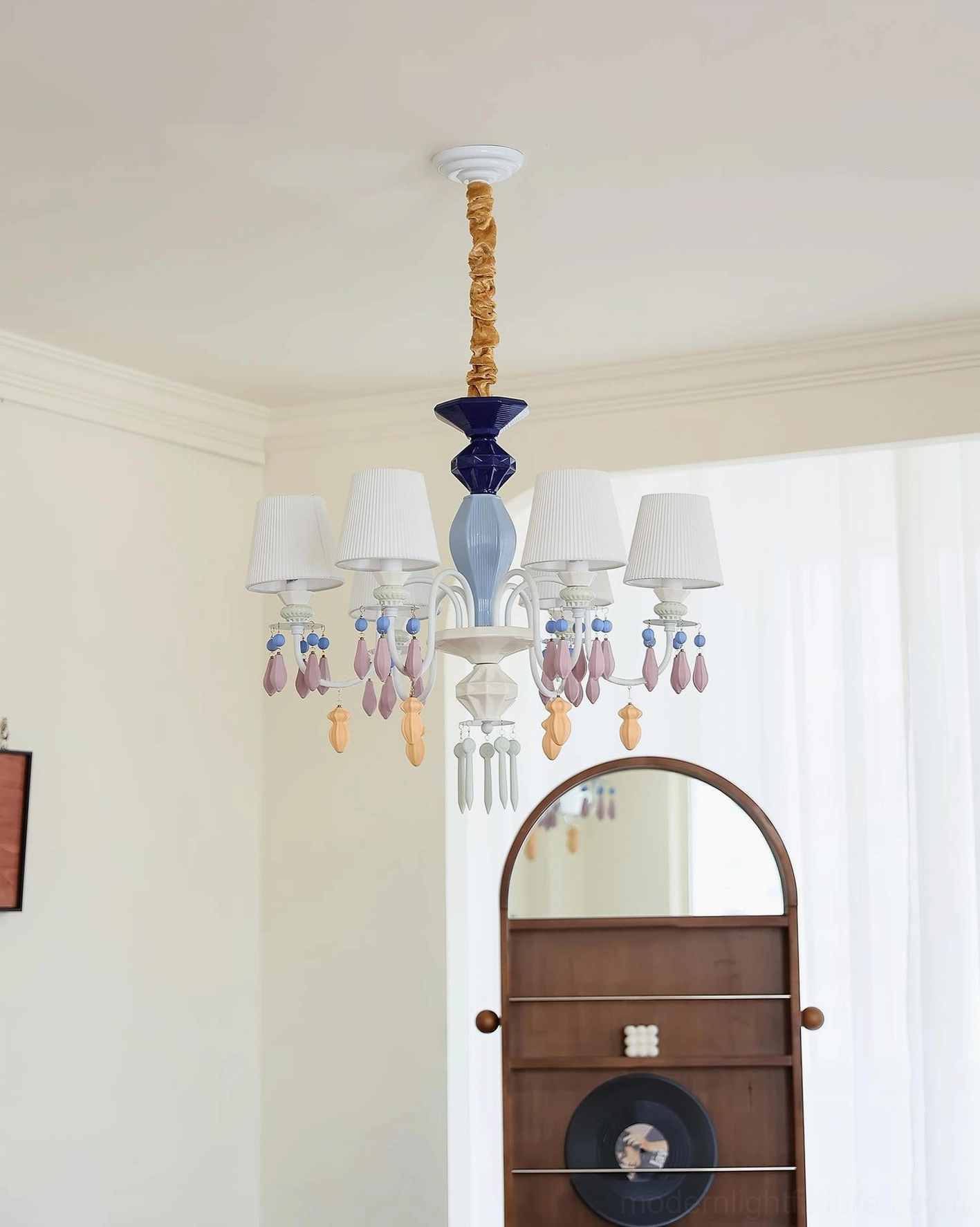 Side view of multi-arm ceramic pendant chandelier with sculptural bead details in bedroom setting