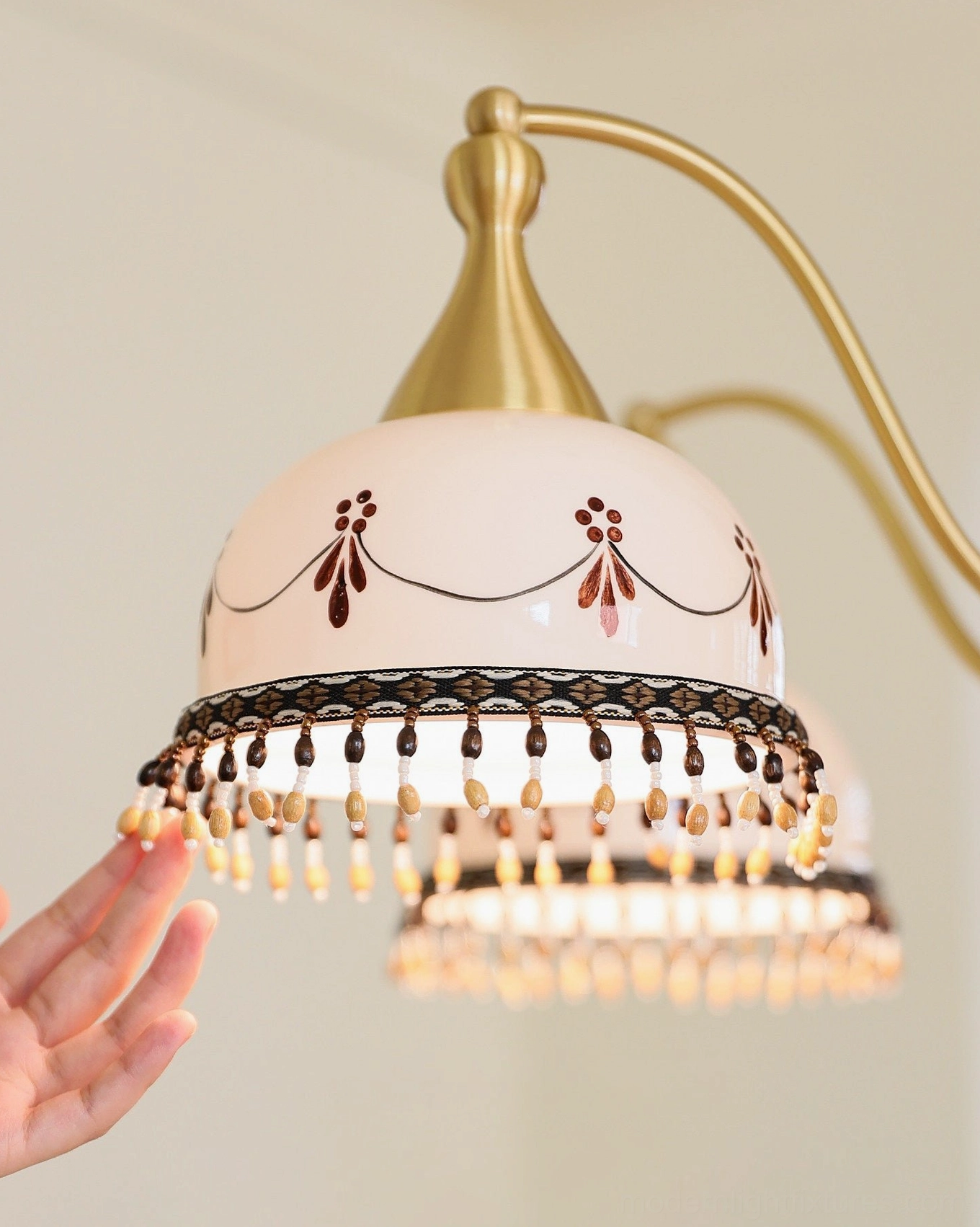 Walnut-toned wood column and brass frame close-up of hand-painted ceramic chandelier