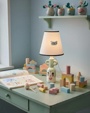 Playful ceramic character table lamp glowing on a child's desk with building blocks showcasing warm ambient lighting