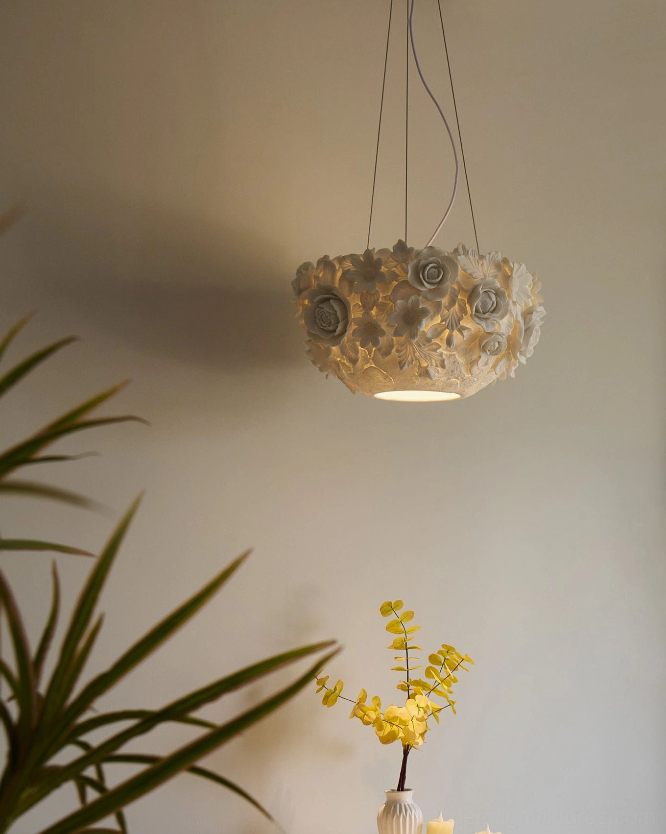 Handcrafted ceramic flower pendant lamp hanging in cozy corner with plant décor and table, warm illuminated ambiance