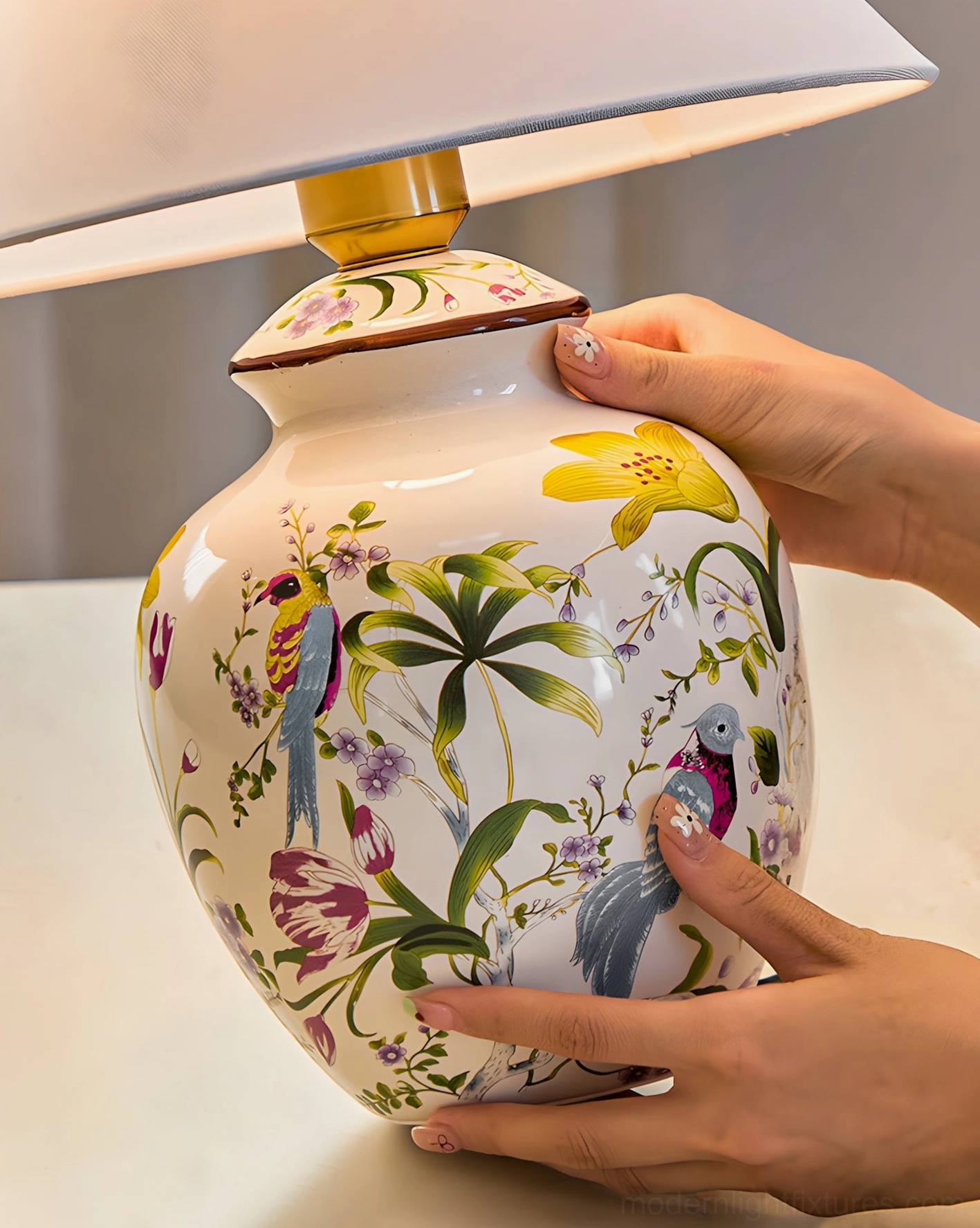 Close-up detail of ceramic table lamp base showcasing intricate hand-painted floral and bird pattern on white porcelain with colorful botanical prints
