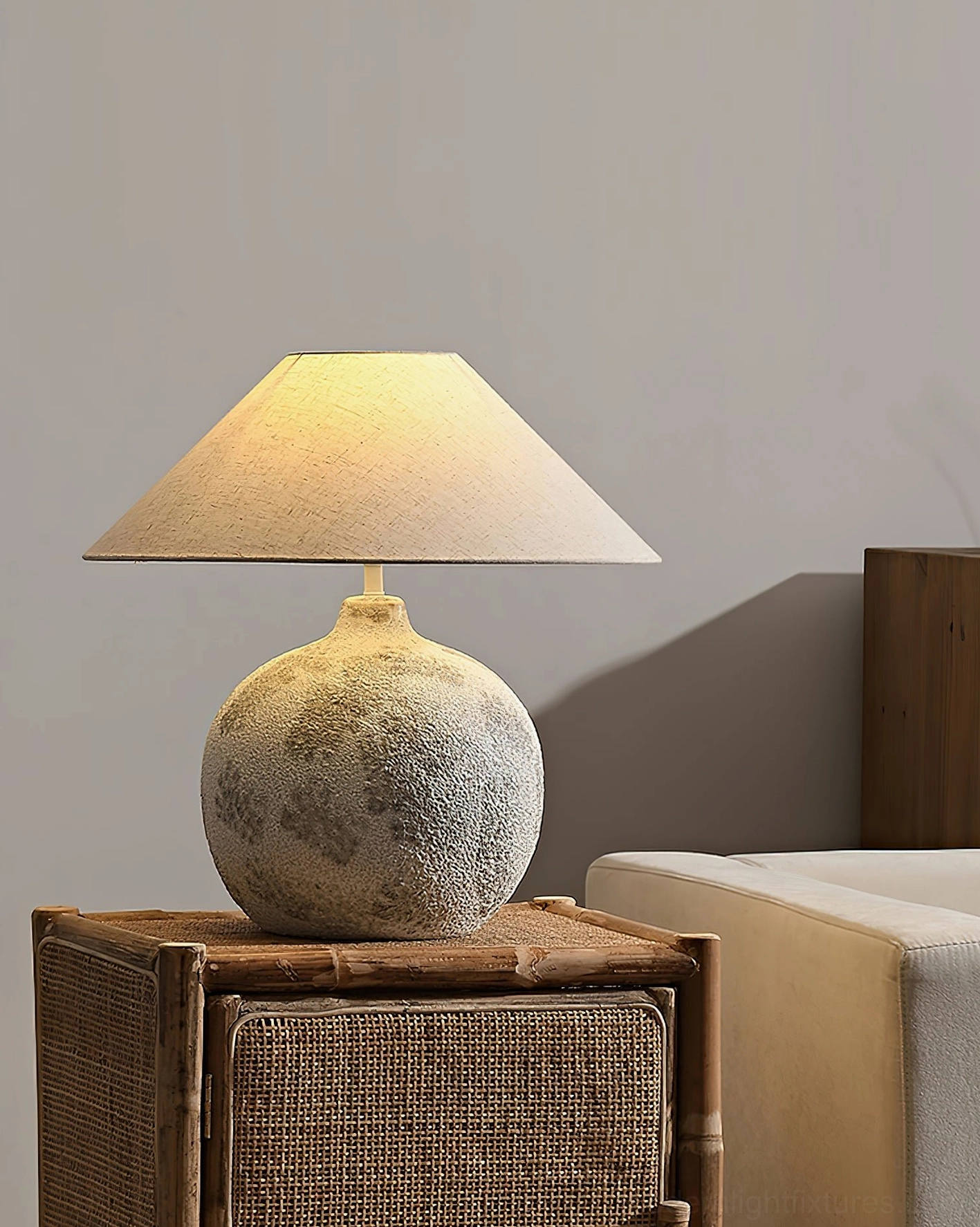 Right three-quarter view of ceramic table lamp on rattan side table in minimalist living room with sofa and contemporary furnishings