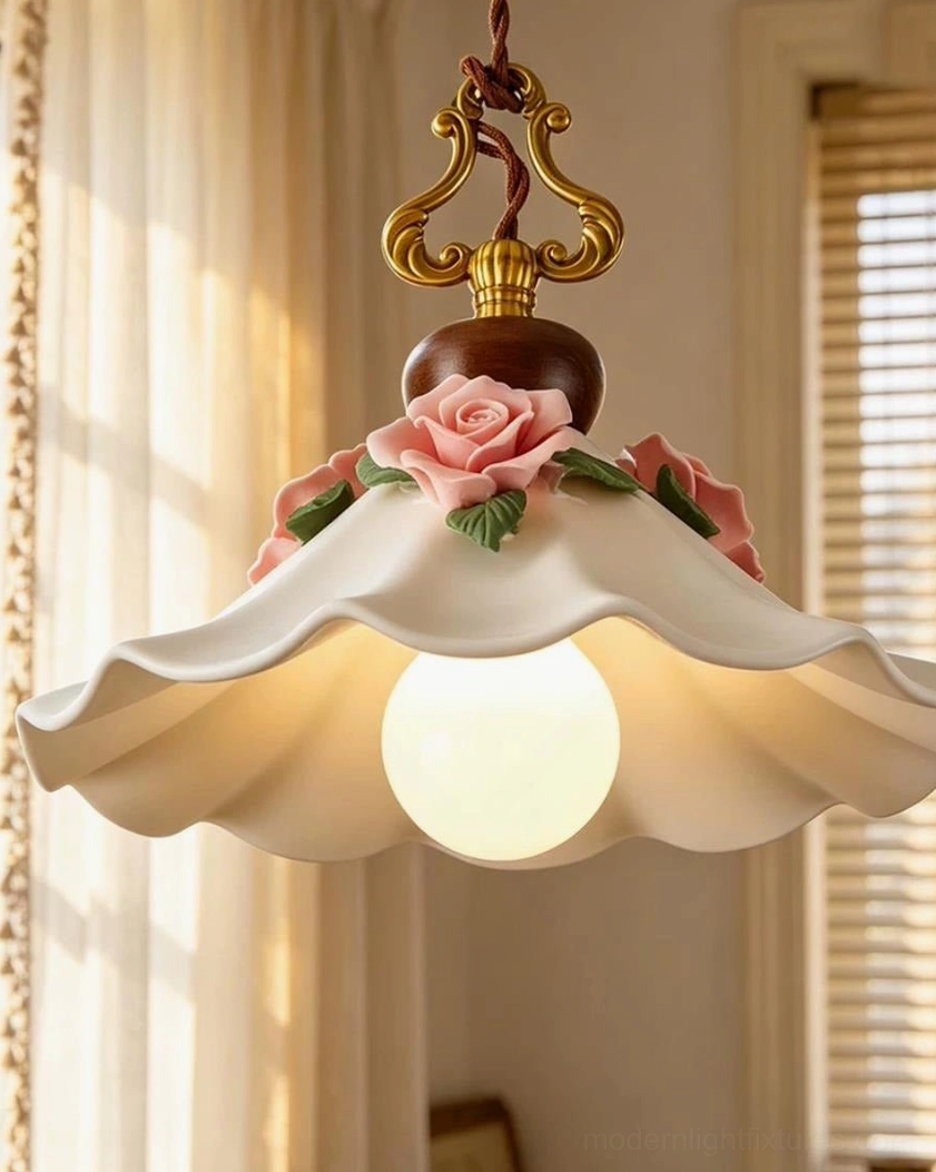 Close-up studio view of ceramic pendant shade with ornate brass hardware and pink rose appliqué details