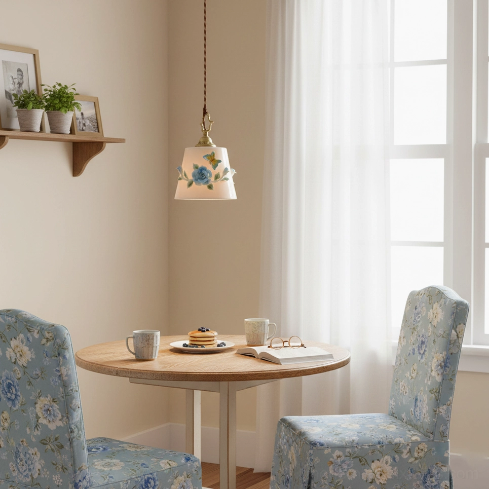 Single handpainted ceramic pendant lamp in cozy cottage dining nook with wooden round table and floral upholstered chairs, creating intimate botanical ambiance