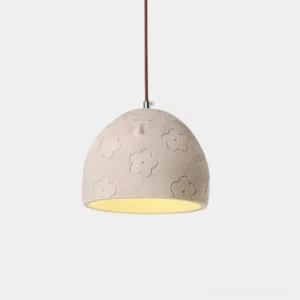Beige matte ceramic sculptured face pendant lamp with embossed floral detail and brown fabric cord hanging against white background