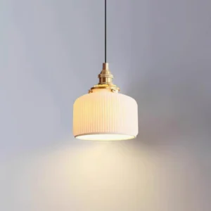 Modern ceramic pendant lamp emitting warm ambient light, eye-level view showcasing ribbed shade and brass fixtures