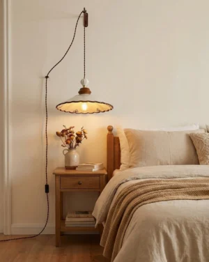 Hand-painted ceramic pendant light hung at bedside in warm bedroom setting with rustic neutral decor and glowing ambient light