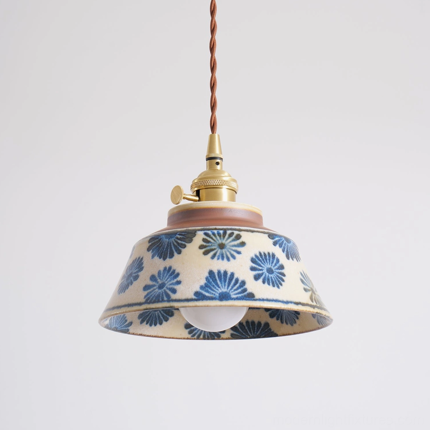 Close-up of brass fittings and twisted fabric cord on hand-painted ceramic pendant light